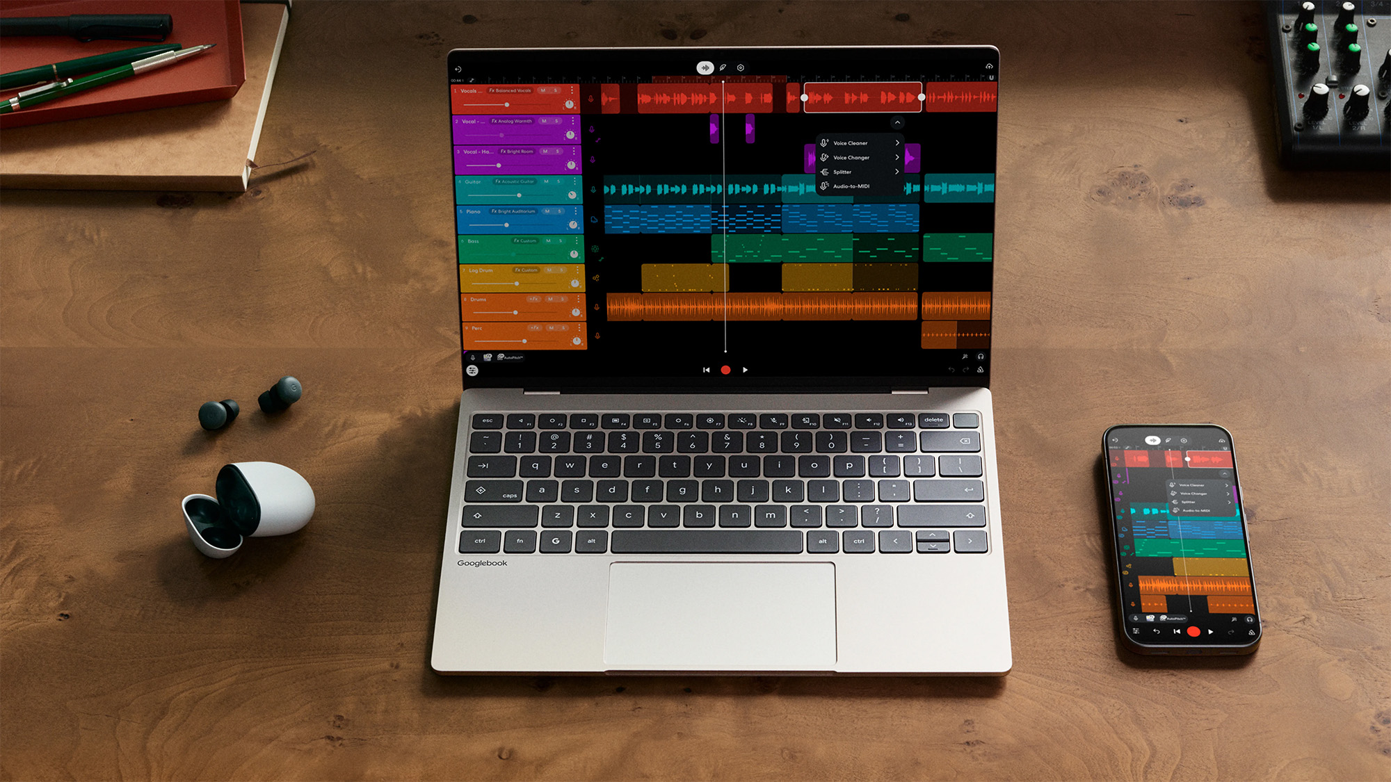 Unbranded Googlebook laptop on a wooden desk with earbuds and smartphone