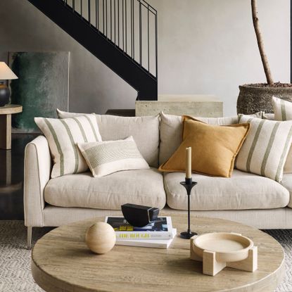 A living room with a light-coloured sofa with milti-coloured cushions