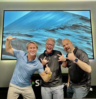Three people pose and smile, happily celebrating the return of Blake Vackar at Screen Innovations.
