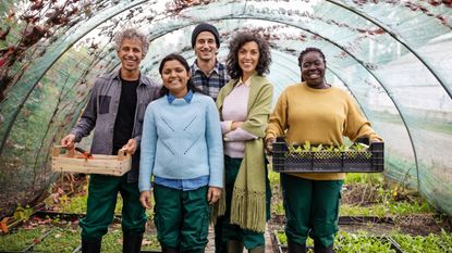 Group of people stand in greenhouse with baskets of produce