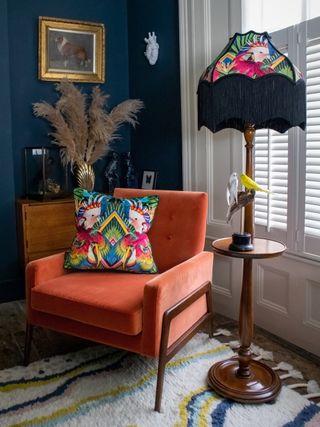 living room corner ideas with tasselled printed floor lamp, orange chair and printed cushion by Divine Savages