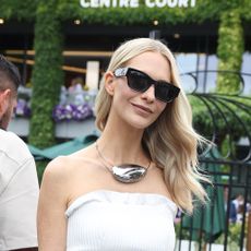 Poppy Delevingne wearing a white tube top, black wide-leg pants, sunglasses, and collar pendant necklace