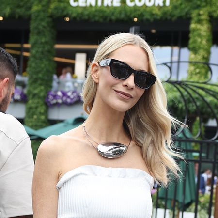 Poppy Delevingne wearing a white tube top, black wide-leg pants, sunglasses, and collar pendant necklace