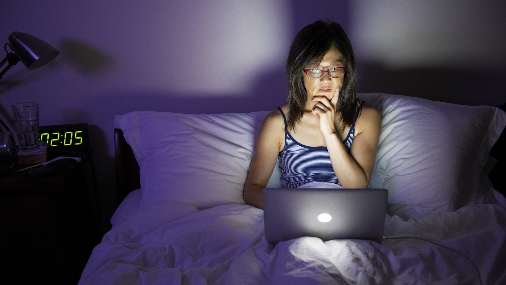 A woman sits up in bed unable to sleep