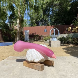Phallic sculpture resting on a rock, on two wooden beams