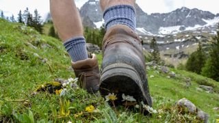 A hiker walking through a hill wearing hiking socks and boots
