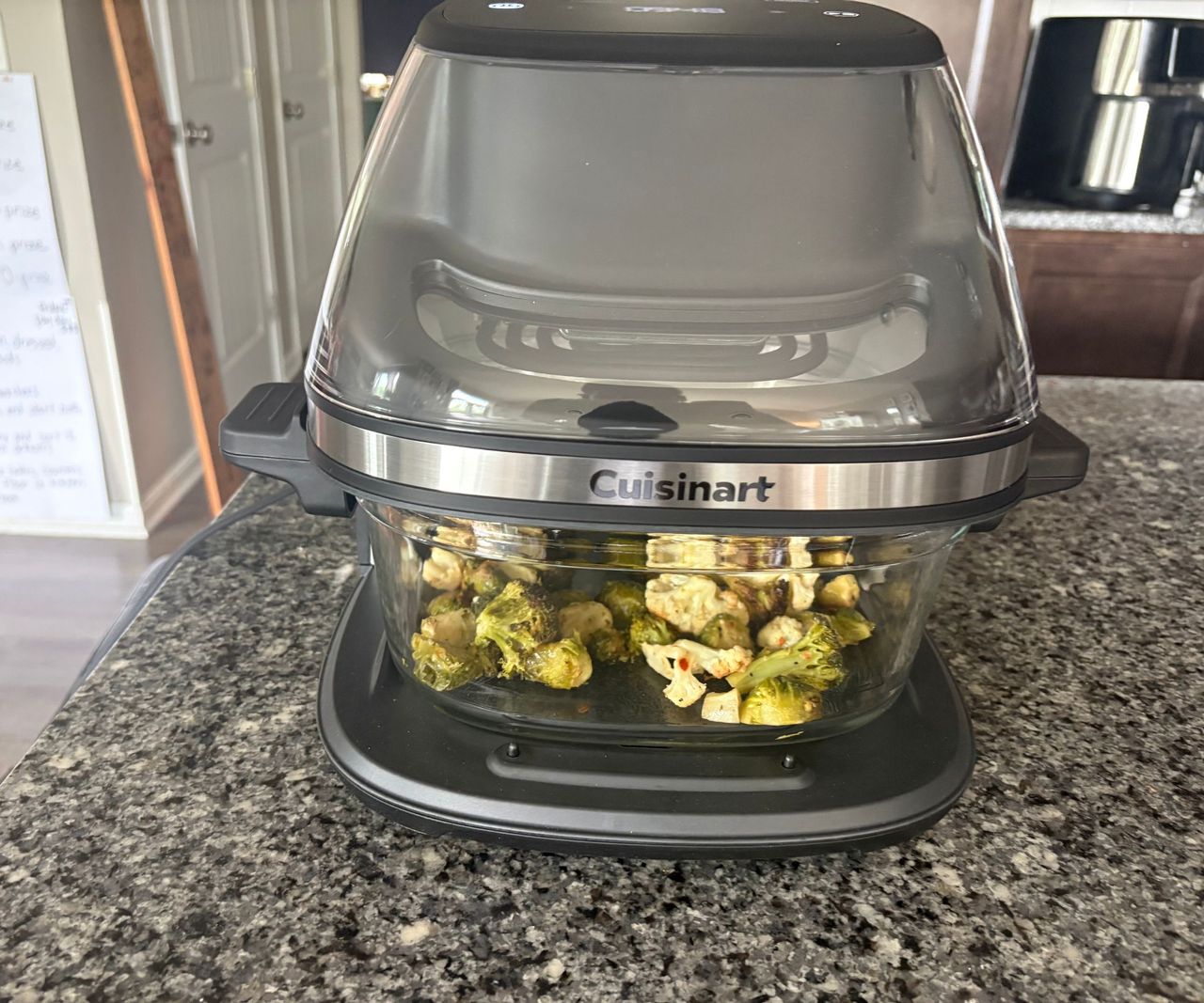 The Cuisinart glass air fryer on a granite countertop frying vegetables.