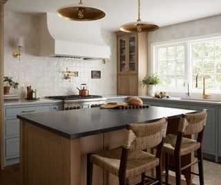 A wood, white, and blue kitchen with a wooden island topped with a black soapstone countertop