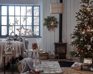 A Scandinavian-inspired Christmas living room with wooden LED stars, Christmas tree and lit wreath