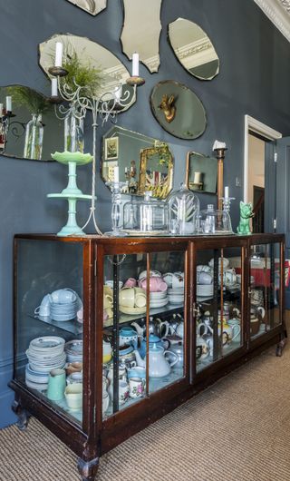 Vintage sideboard filled with crockery sitting in front of a wall of mirrors