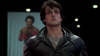 Rocky in a leather jacket with a poster of Apollo behind him