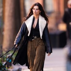 Emily Ratajkowski wearing a fur-lined leather winter coat with plaid pants 