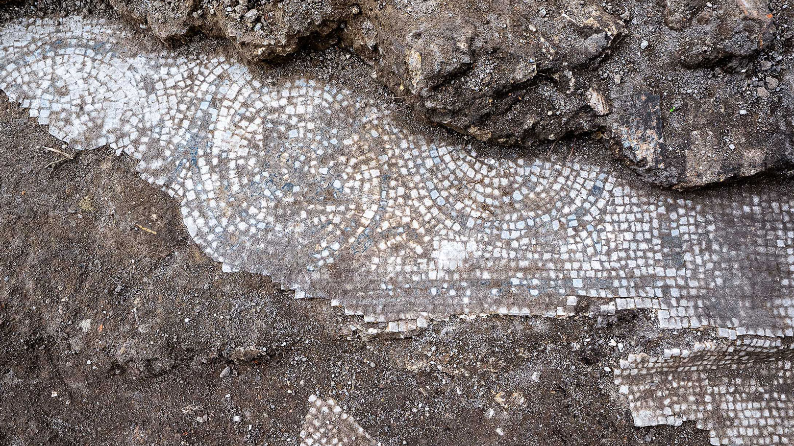archaeologists work at an ancient Roman site revealing mosaic floors and frescoed walls of a villa