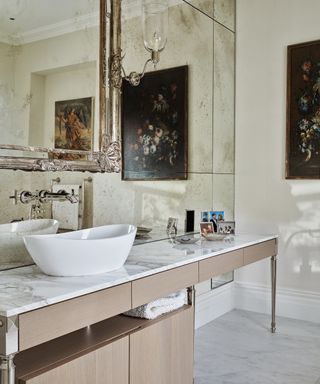 A bathroom with marble effect worktops and a white sink in front of a large mirror