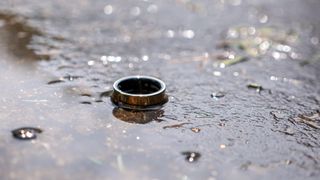 The gold Samsung Galaxy Ring in a puddle of water