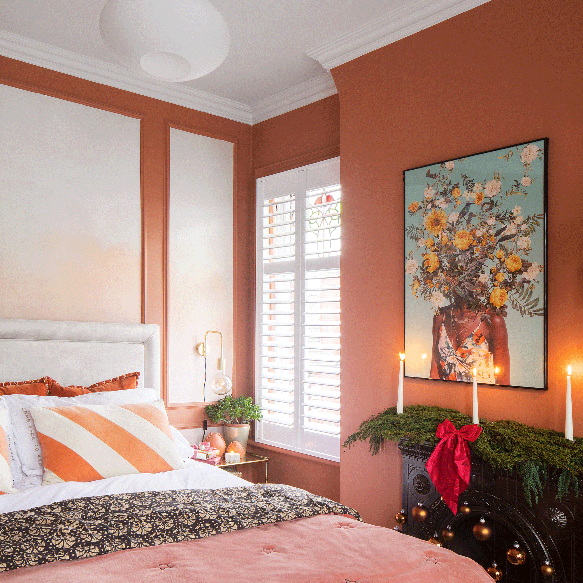 an orange bedroom with shuttered windows pink/orange bedspread orange striped cushion and striking floral artwork