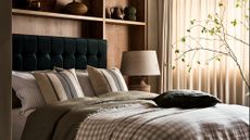 A green upholstered bed built into wooden shelving