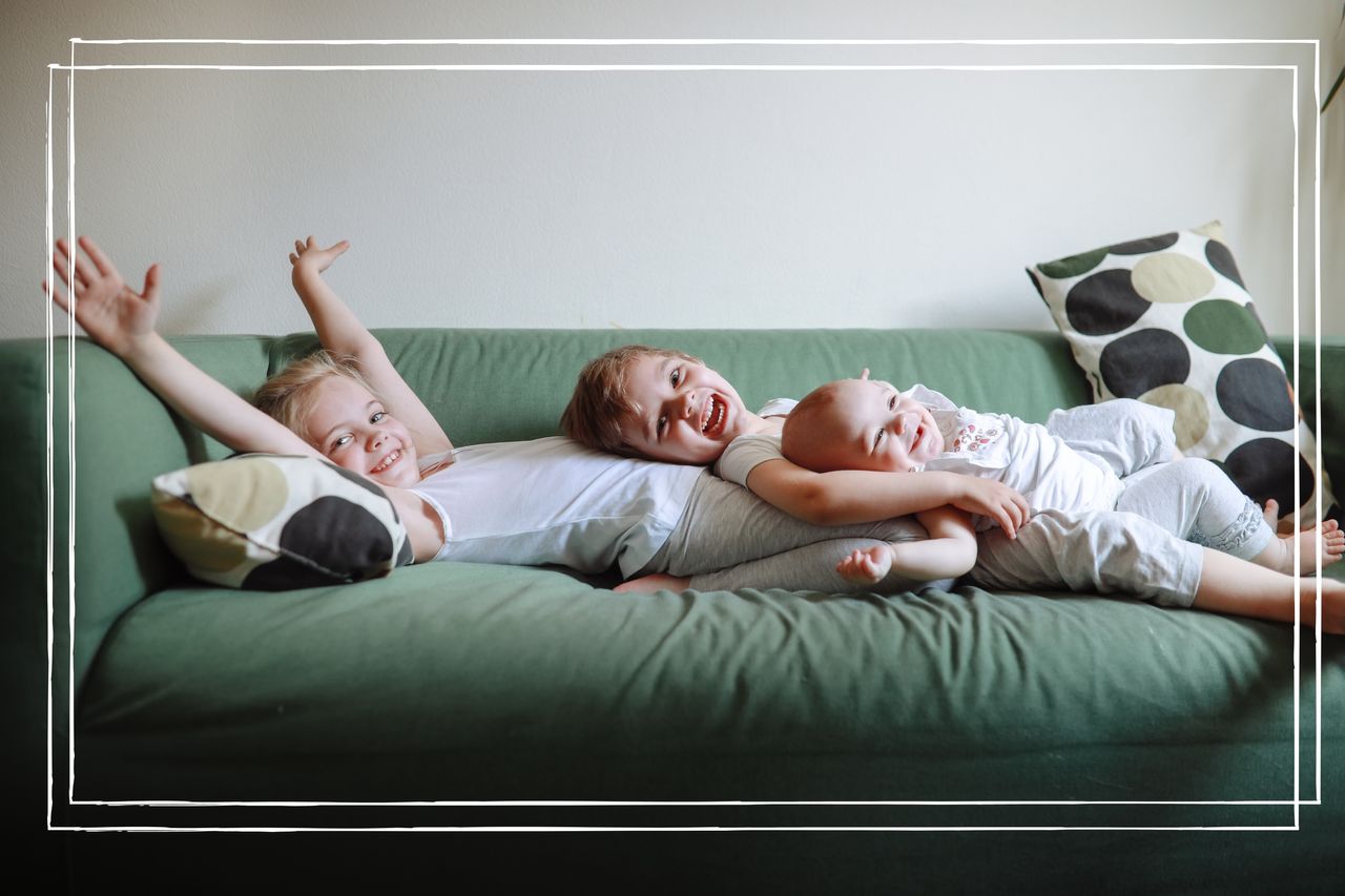 Three sibling children together on green sofa at home. 