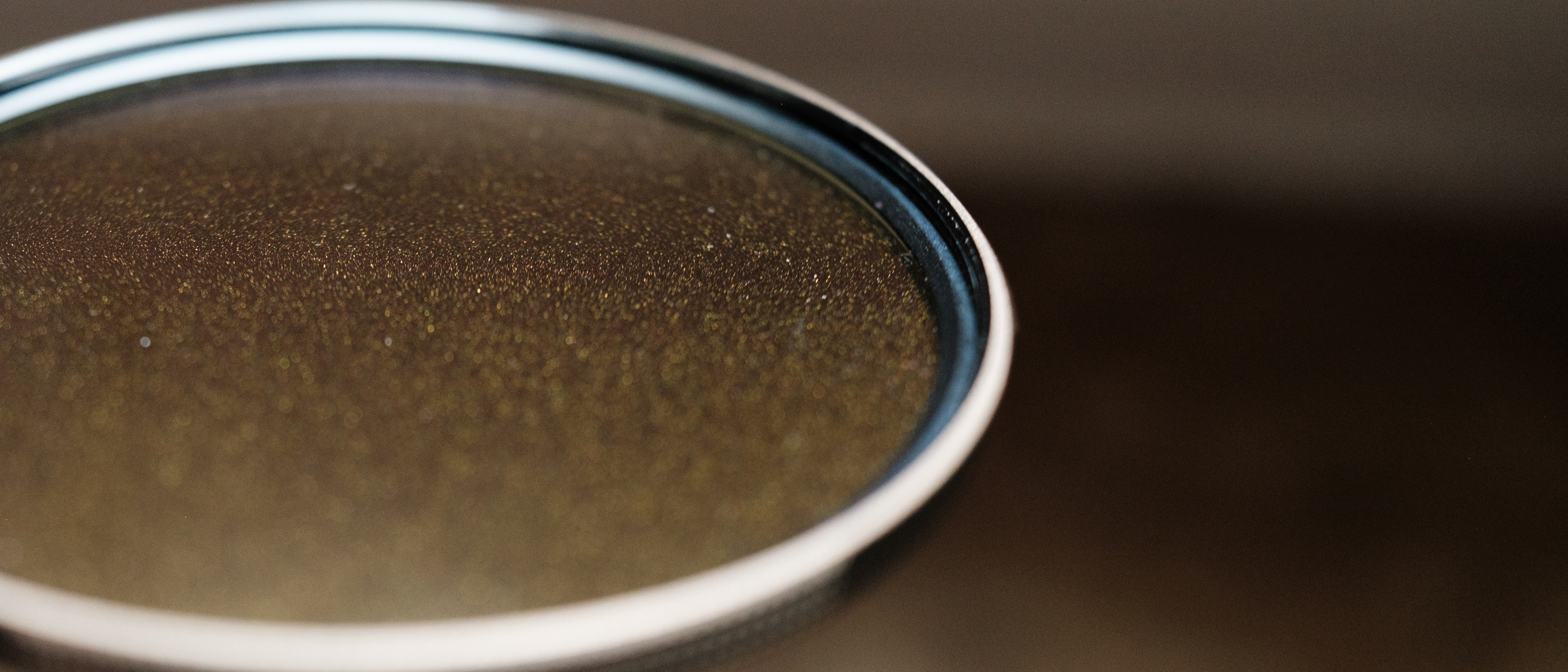A close-up of the PolarPro McKinnon 135 Gold Mist filter showing tiny gold flecks embedded in the glass