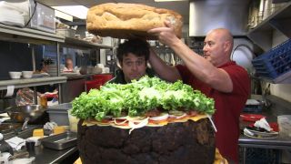 Adam Richman hiding between the biggest burger challenge