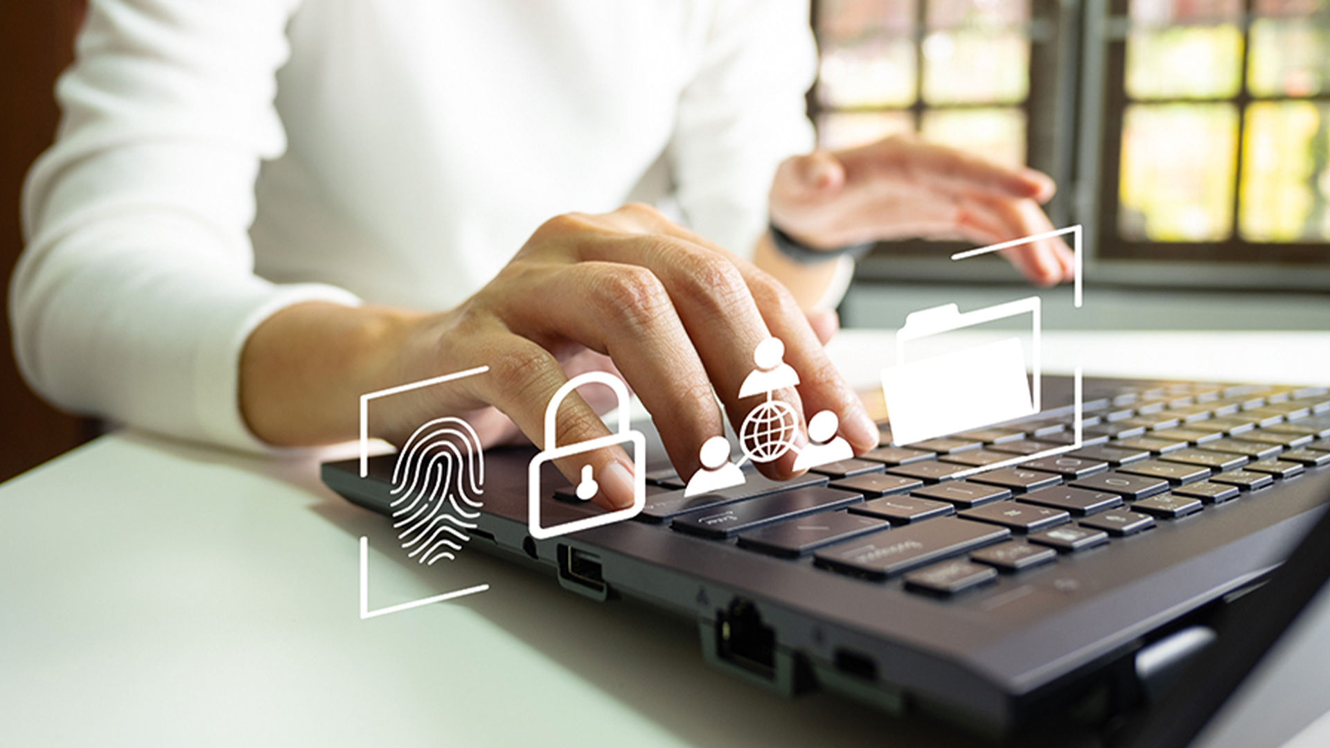A person types on a laptop, with various cybersecurity-related icons hovering above the keyboard