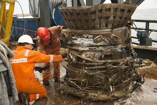 Bezos Expeditions crew members work with the thrust chamber of a recovered F-1 rocket engine from the Saturn V rocket that launched one of NASA's historic Apollo moon missions in this photo.