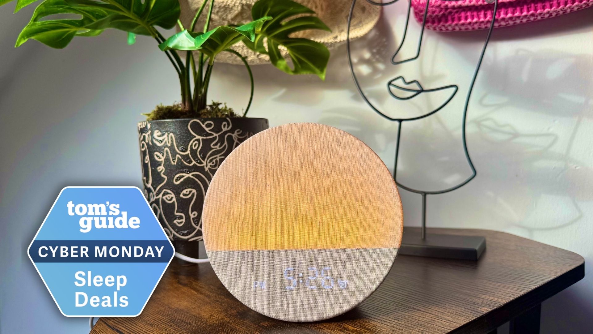 Dreamegg sunrise alarm clock with orange light on bedside table with plant and wire ornament