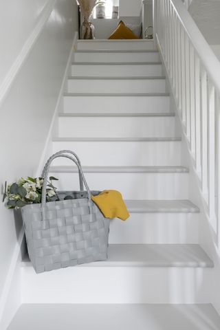 a staircase painted in gray and white tones with a gray bag full of flowers at the bottom of the stairs