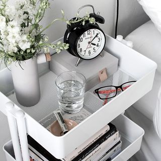 White trolley being used as bedside table displaying everyday essentials