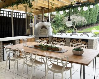 A covered patio dining area with built in pizza oven