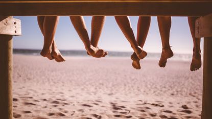 Products for footcare - friends dangling legs over boardwalk at beach 471881510