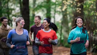 Women running a 5km Park Run together through a forest, one of the best New Year's resolution ideas for 2024