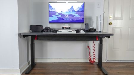 The Herman Miller Coyl Gaming Desk set up in a corner with a PC, monitor and other accessories on top