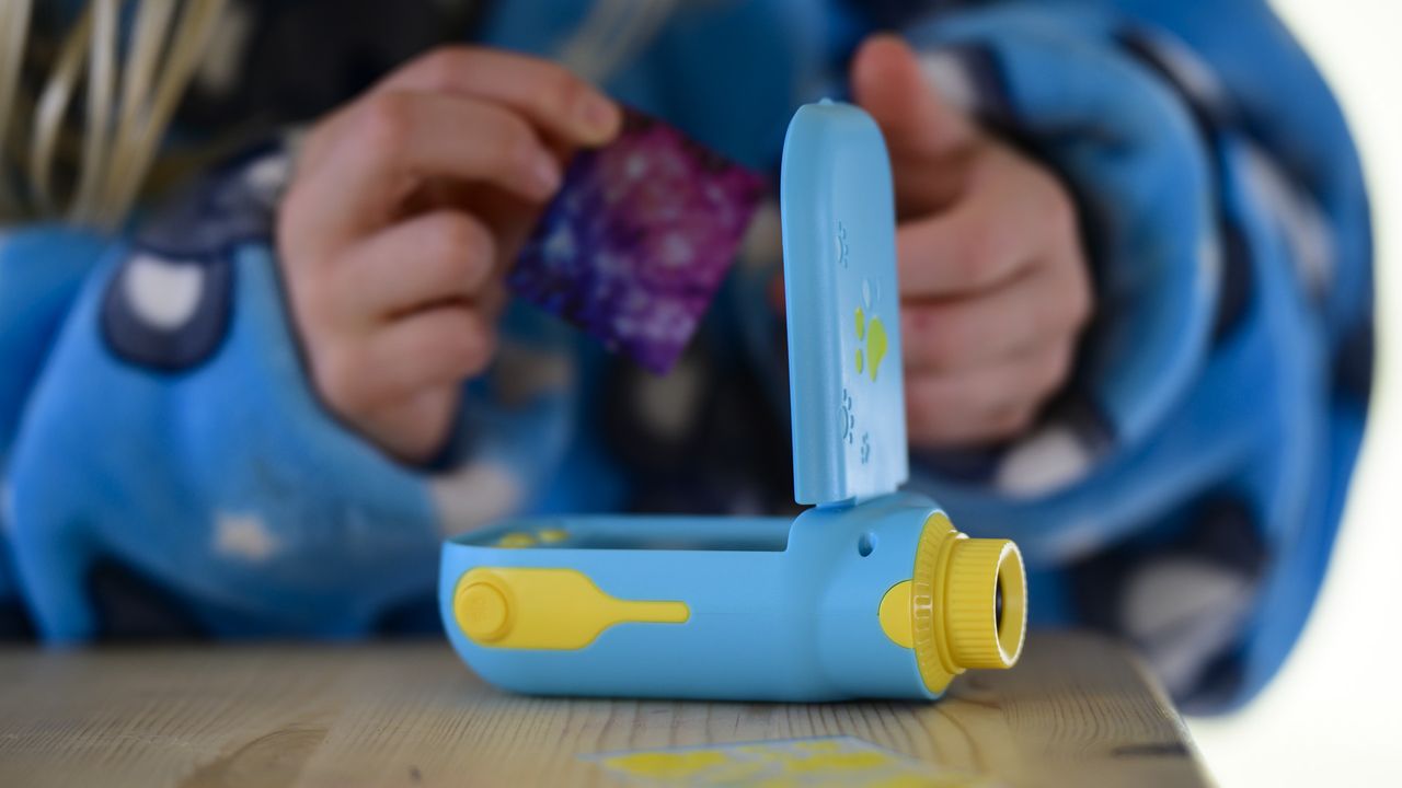 Cheap blue kids camera in the hand adding stickers