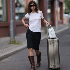 BERLIN, GERMANY - JULY 11: Lea Naumann is seen wearing black sunglasses from Prada, a white tee from Mother Denim, a black knee-length vintage skirt, brown leather boots with silver buckle closure from Miu Miu, a white leather Supernova bag from Prada and a silver suitcase from Rimowa on July 11, 2023 in Berlin, Germany. (Photo by Jeremy Moeller/Getty Images)