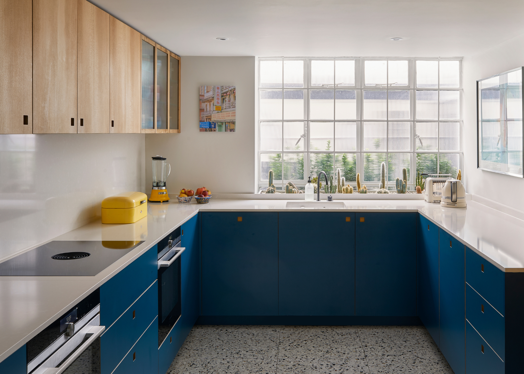 small kitchen with navy cupboards and white counters with wooden upper cabinets