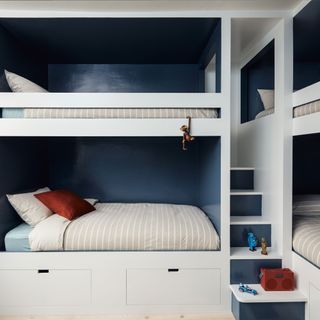Blue boys bedroom with built-in bunk beds and storage, striped bedding and rust accents
