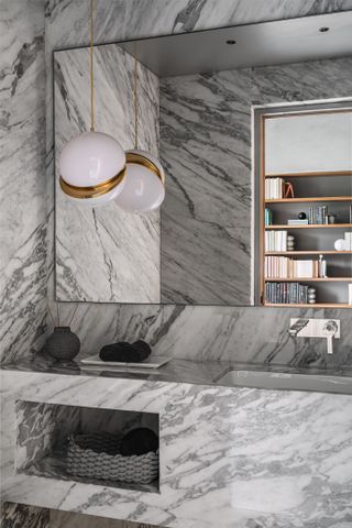 A bathroom with veined marble walls and vanity