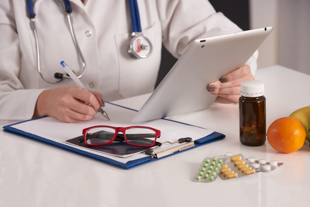 A doctor writing up a digital prescription via a tablet device