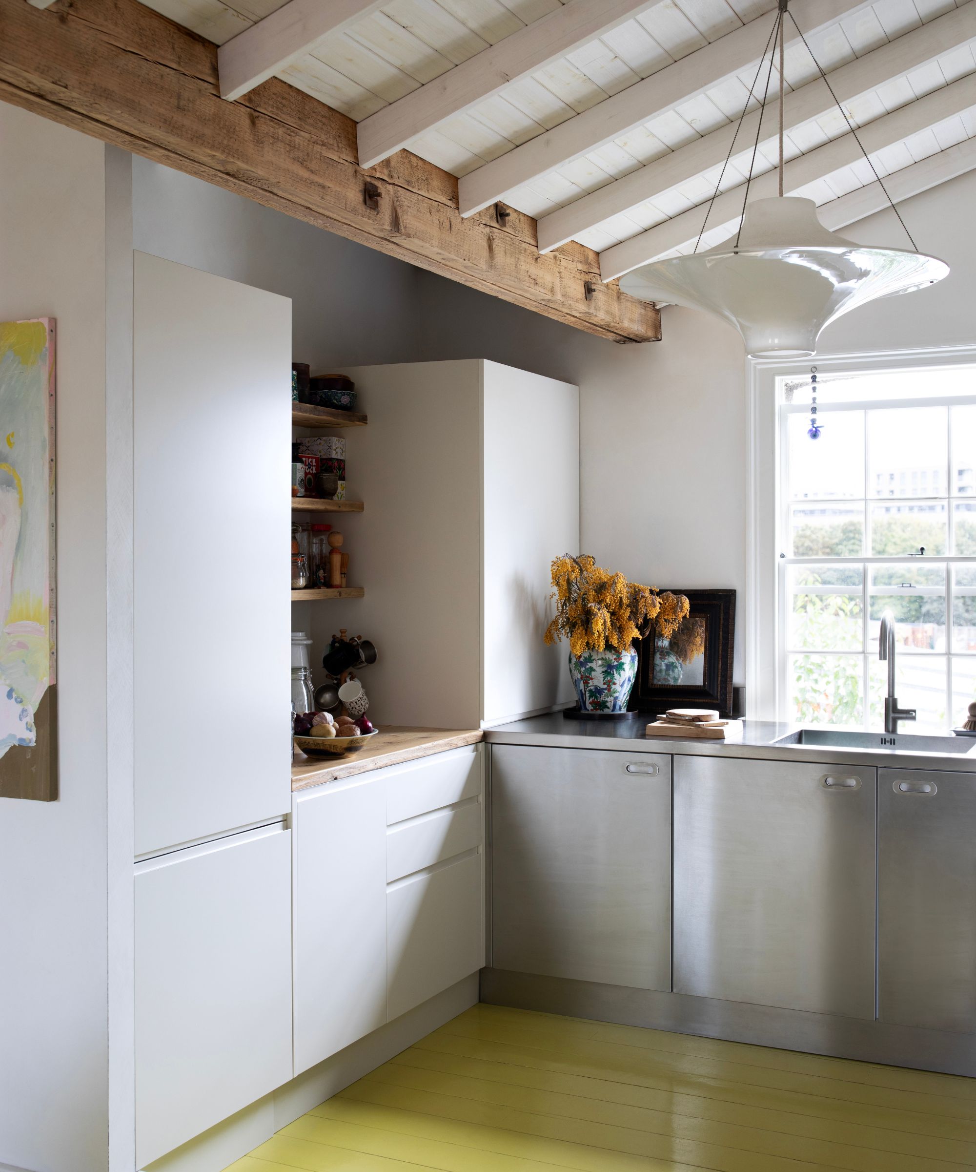 A small kitchen with white and stainless steel cabinets and a lime green floor