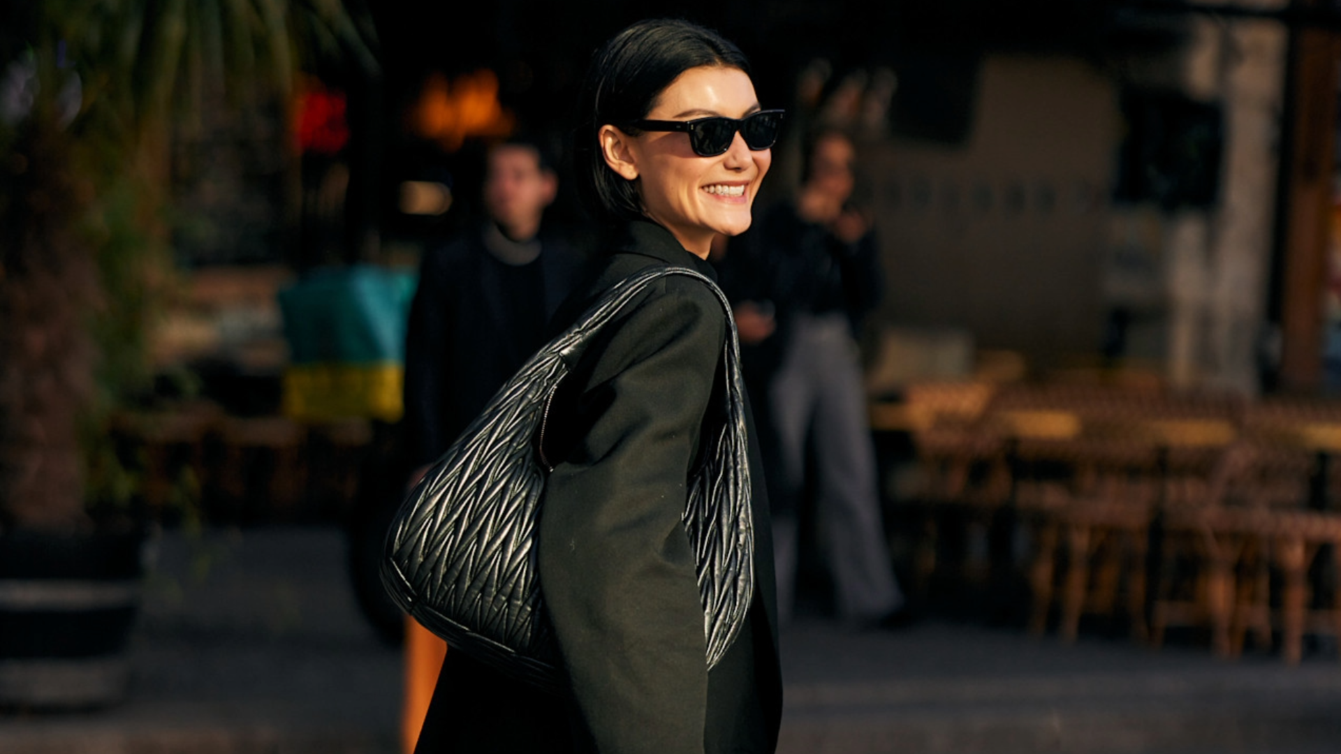 woman in paris carrying a black tote and wearing a black jacket and sunglasses 