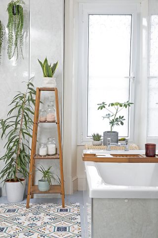 Bathroom with grey panel walls, patterned tile effect flooring, wooden shelving unit and wooden bath caddy