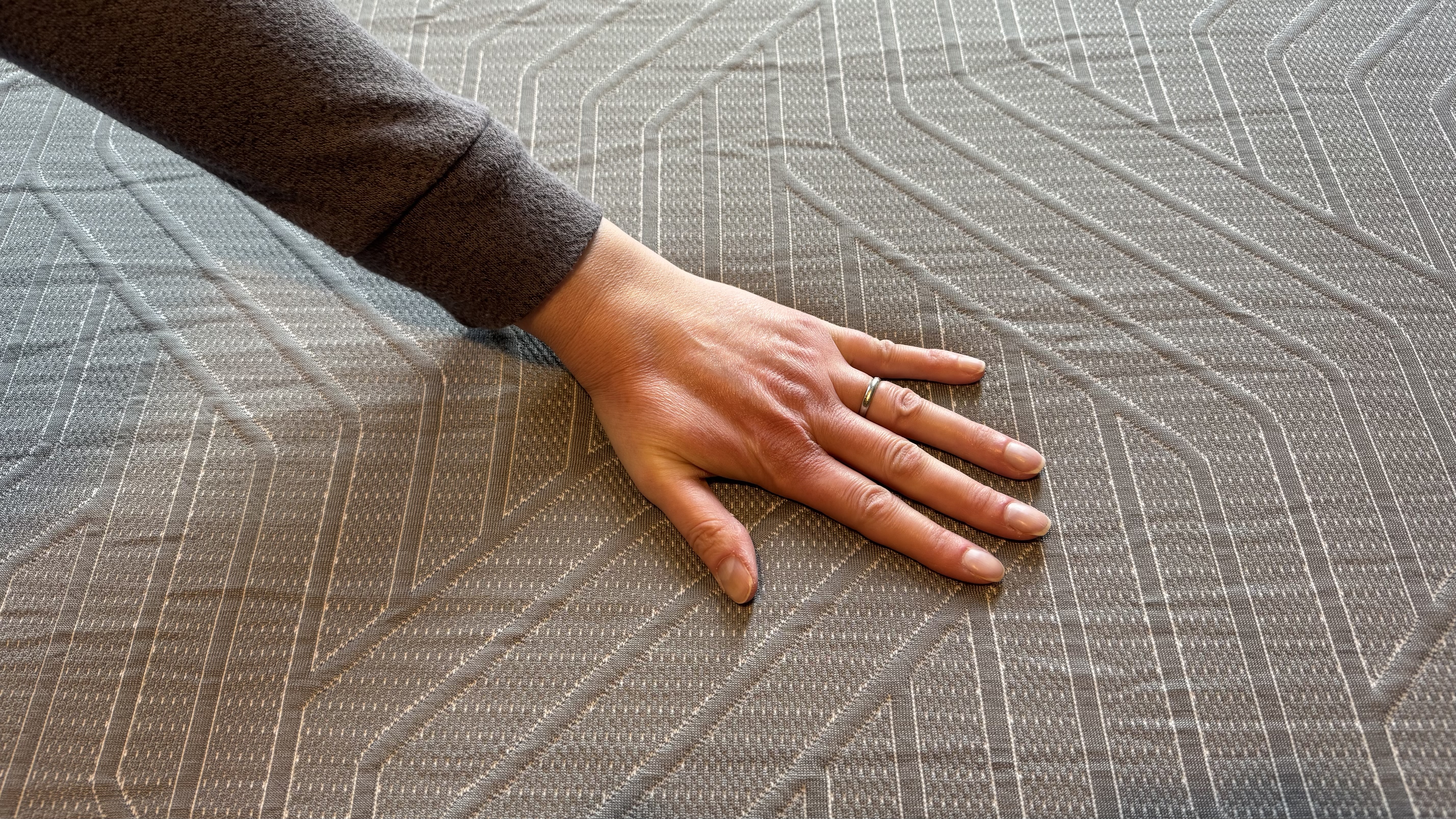 A hand pressing on the EGOHOME Hybrid mattress.