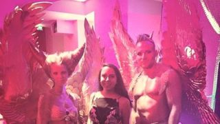 Posing with models wearing gold body paint and huge gold wings in pink lighting