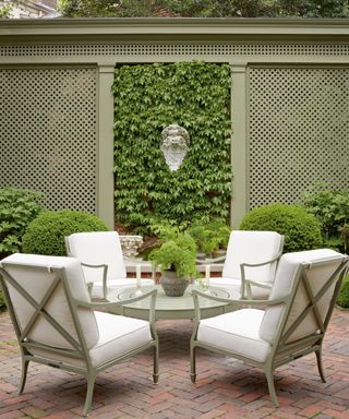 McKinnon and Harris Beaufort club chairs with white cushions on patio in garden with trellis