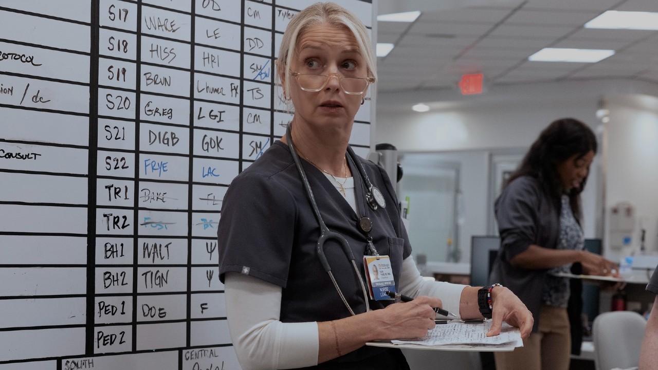 क्लिप बोर्ड आणि पेन धरून दाना तिच्या चष्म्यातून वर पाहत आहे.