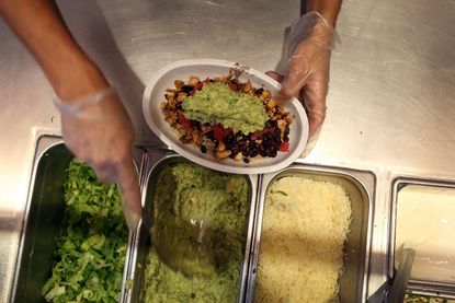 Chipotle worker scooping guacamole