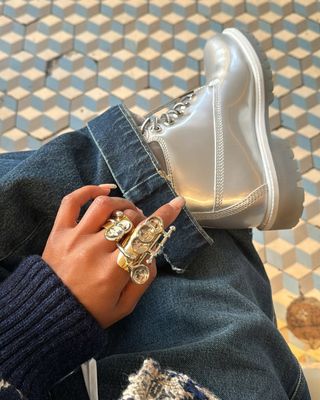 woman wearing cuffed denim outfit with silver sneakers and silver rings