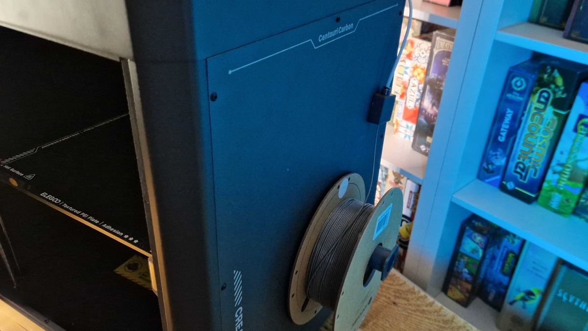 Side of the Elegoo Centauri Carbon with filament, all against a set of board game shelves
