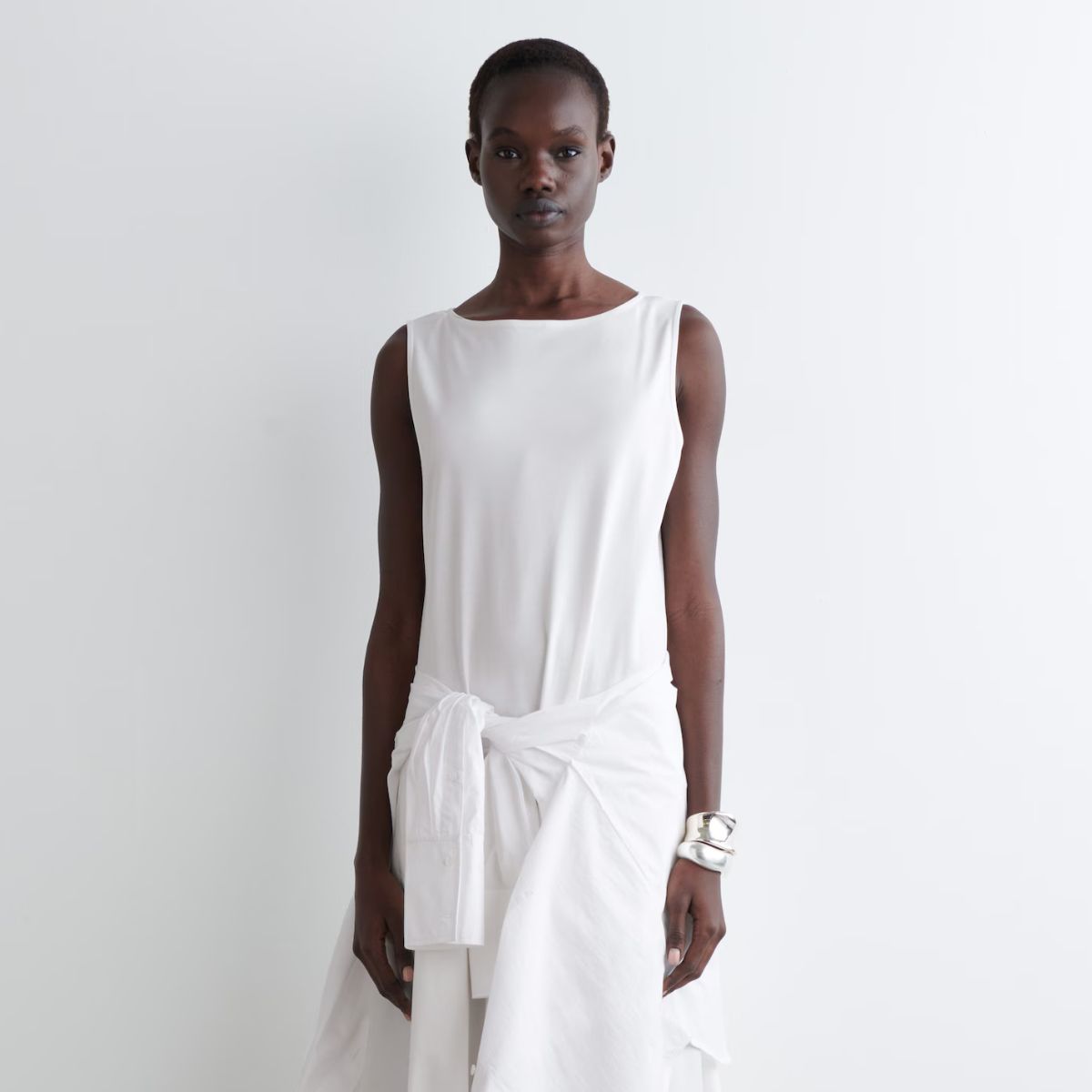 Woman wears white dress and white shirt tied around the waist
